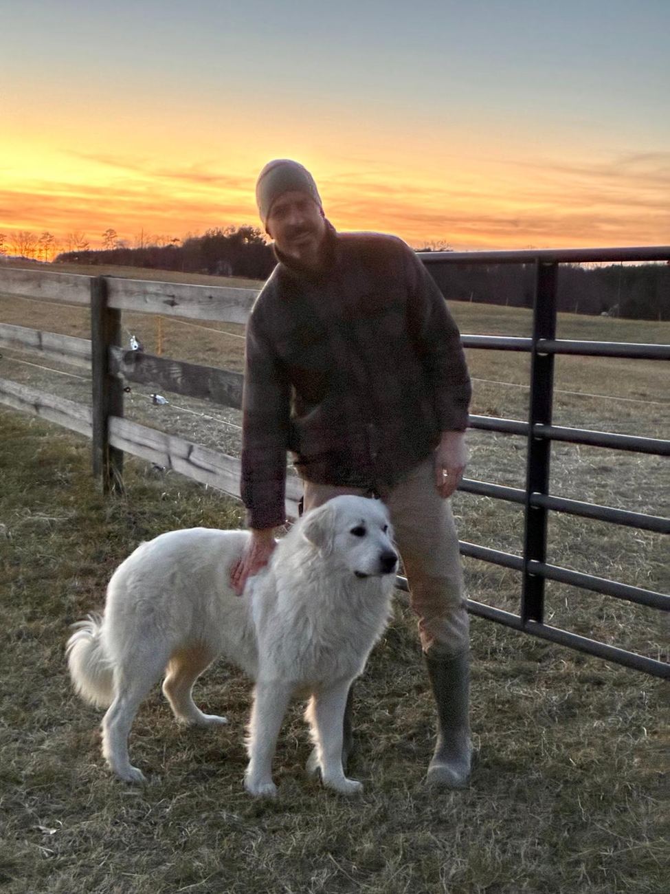 A Forza Ranch farmer with his guardian dog at sunset by the pasture fence